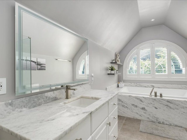 bathroom with tile patterned floors, tiled tub, vanity, and lofted ceiling