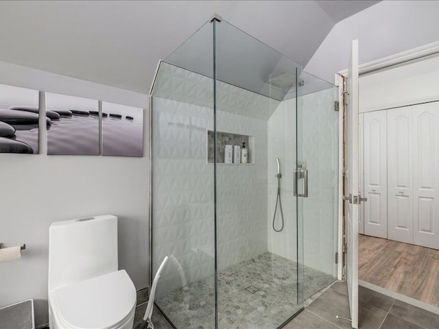 bathroom featuring toilet, a shower with shower door, vaulted ceiling, and hardwood / wood-style flooring