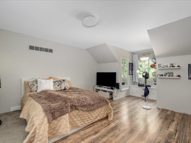 bedroom with vaulted ceiling and hardwood / wood-style flooring