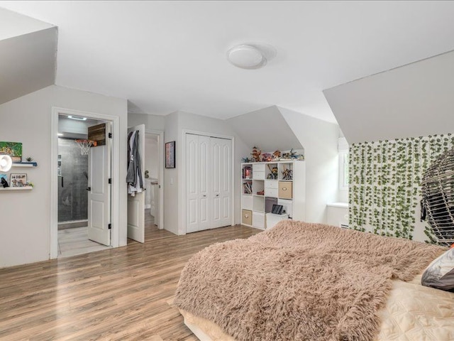 bedroom featuring connected bathroom, light hardwood / wood-style flooring, and lofted ceiling