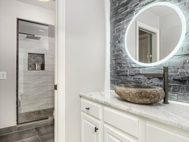 bathroom with vanity, tasteful backsplash, and a shower with door