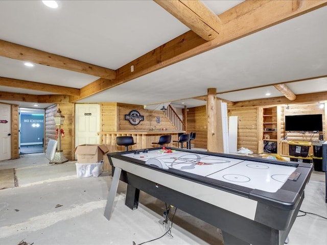 recreation room featuring beam ceiling and wood walls