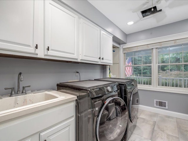 clothes washing area with cabinets, sink, light tile patterned flooring, and washing machine and clothes dryer