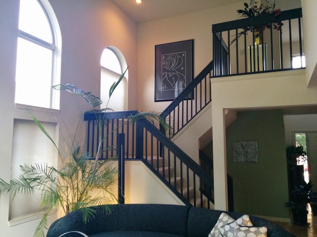 staircase with a towering ceiling and a healthy amount of sunlight