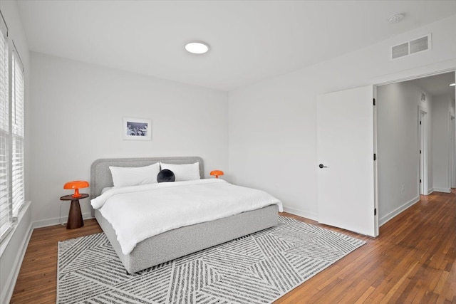 bedroom with multiple windows and dark wood-type flooring