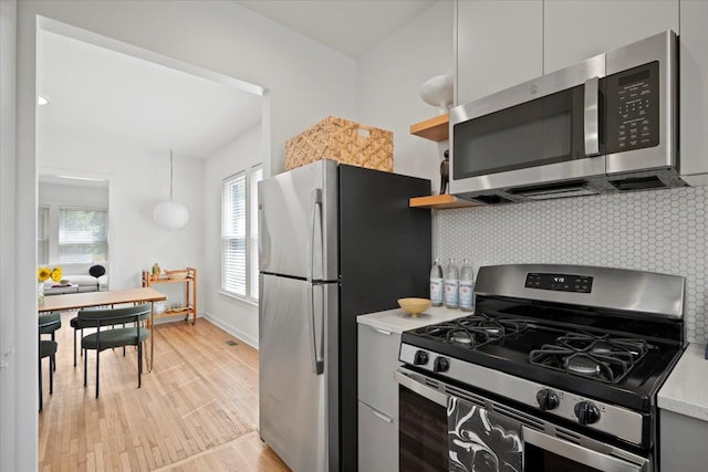 kitchen with backsplash, light hardwood / wood-style floors, and stainless steel appliances