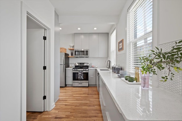 kitchen with decorative backsplash, sink, stainless steel appliances, and light wood-type flooring