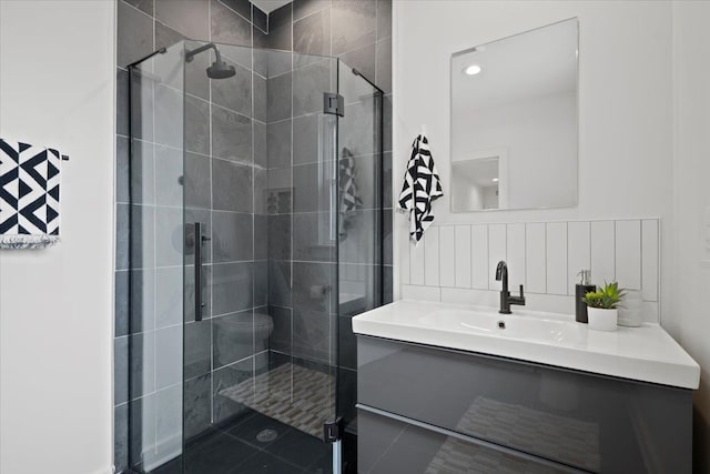 bathroom featuring tile patterned floors, vanity, a shower with shower door, and toilet