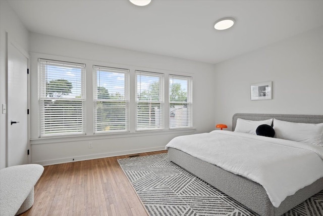 bedroom with hardwood / wood-style flooring and multiple windows