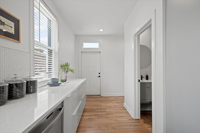 kitchen featuring white cabinets, a healthy amount of sunlight, light wood-type flooring, and tasteful backsplash