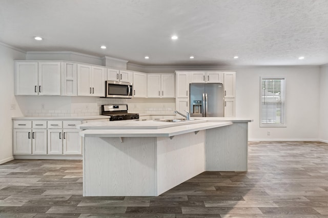 kitchen with white cabinetry, sink, a center island with sink, appliances with stainless steel finishes, and ornamental molding