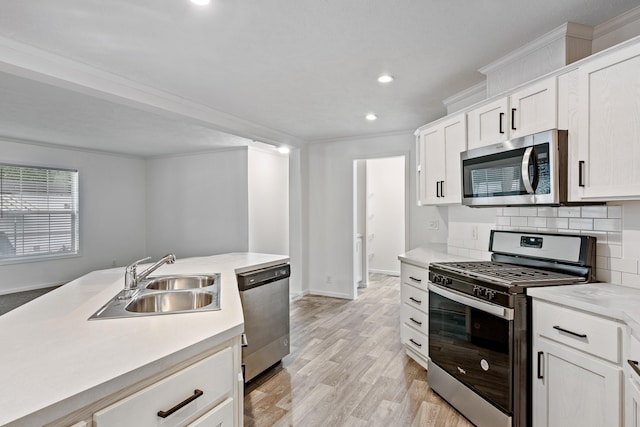 kitchen featuring white cabinetry, sink, light hardwood / wood-style floors, decorative backsplash, and appliances with stainless steel finishes