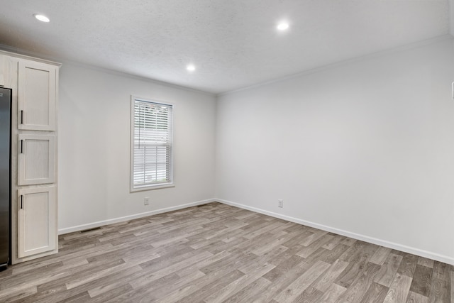 unfurnished room with a textured ceiling and light hardwood / wood-style flooring