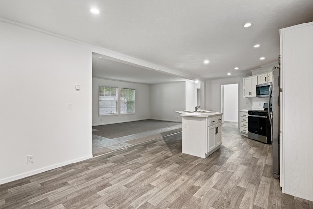 kitchen featuring white cabinetry, an island with sink, light wood-type flooring, and appliances with stainless steel finishes