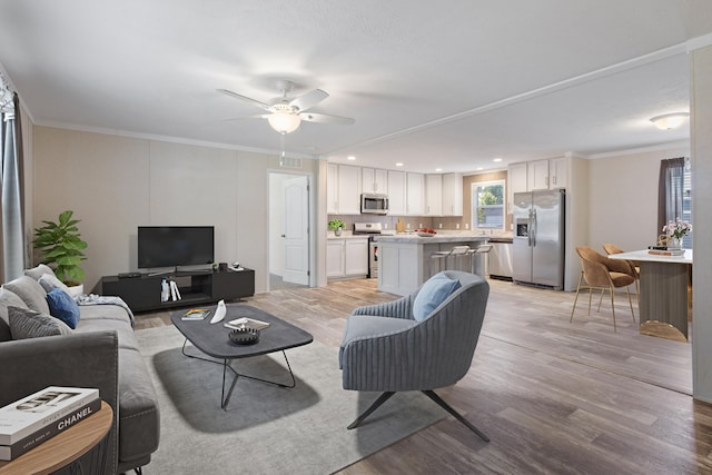 living room with ceiling fan, light hardwood / wood-style flooring, and ornamental molding