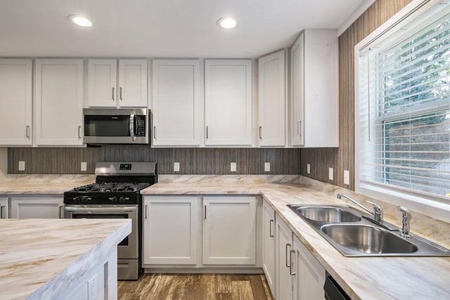 kitchen with a wealth of natural light, white cabinetry, sink, and appliances with stainless steel finishes