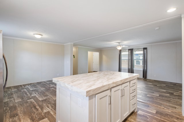 kitchen with white cabinets, a kitchen island, ornamental molding, and dark wood-type flooring