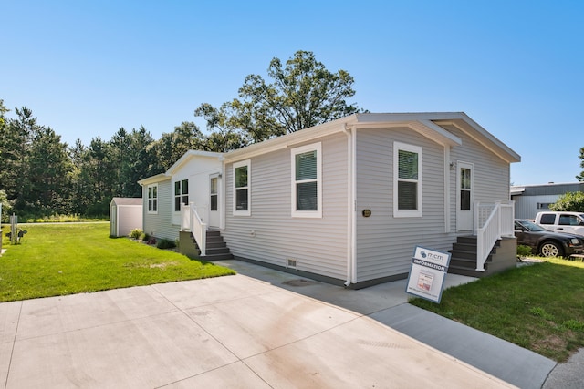 manufactured / mobile home with a front lawn and a storage unit