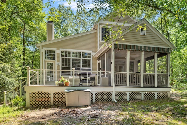 back of property featuring a sunroom, a chimney, and a wooden deck