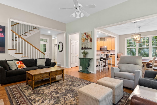 living room with ceiling fan with notable chandelier and wood-type flooring