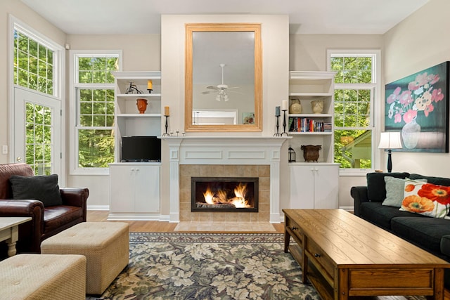 living room featuring a tile fireplace, ceiling fan, plenty of natural light, and hardwood / wood-style flooring