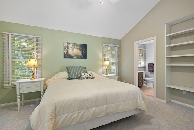 carpeted bedroom featuring ensuite bath and vaulted ceiling