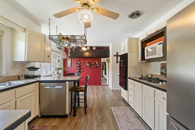 kitchen featuring appliances with stainless steel finishes, dark hardwood / wood-style floors, ceiling fan, and a kitchen breakfast bar