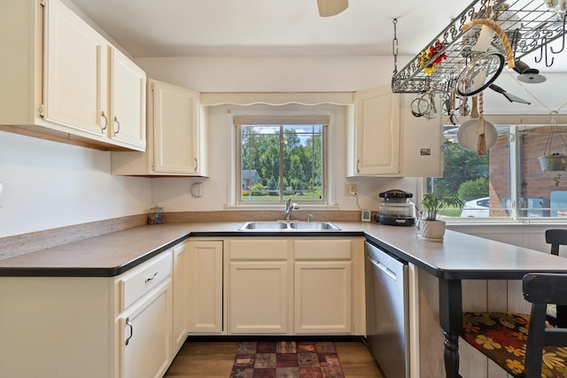 kitchen with kitchen peninsula, dark hardwood / wood-style flooring, stainless steel dishwasher, sink, and white cabinetry