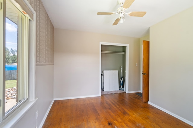 unfurnished bedroom with ceiling fan, dark wood-type flooring, and a closet