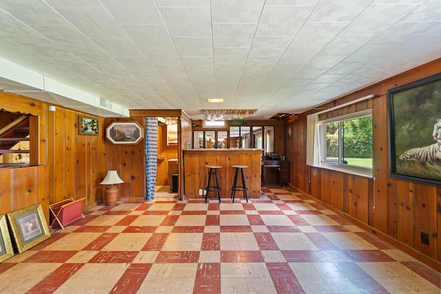 interior space featuring bar and wood walls