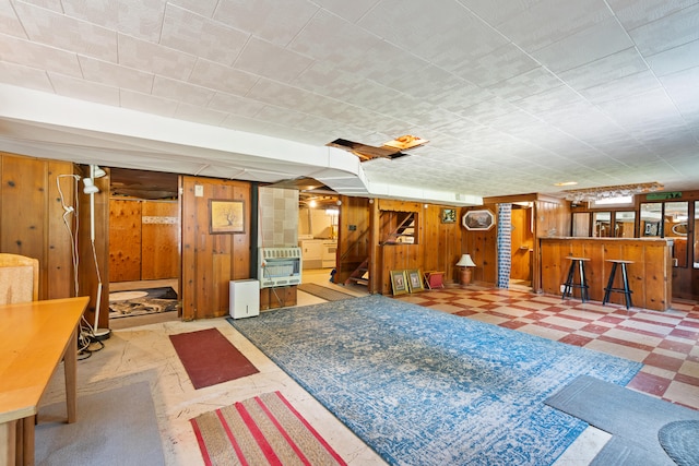 living room with heating unit, wooden walls, and indoor bar