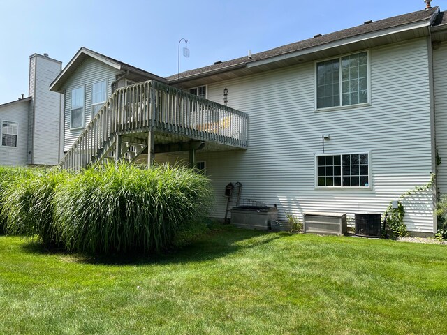 rear view of property featuring a yard, cooling unit, a deck, and stairway