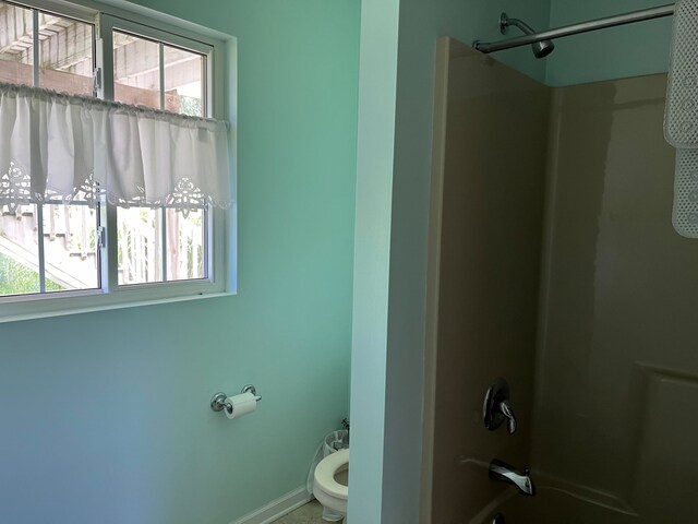 bathroom with shower / bath combination, baseboards, and toilet