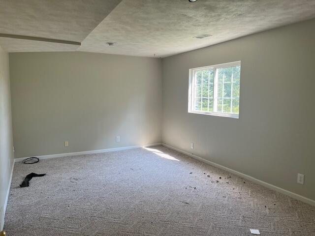 empty room with visible vents, carpet, baseboards, and a textured ceiling