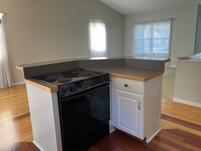 kitchen featuring light wood-style flooring, black electric range oven, and white cabinets