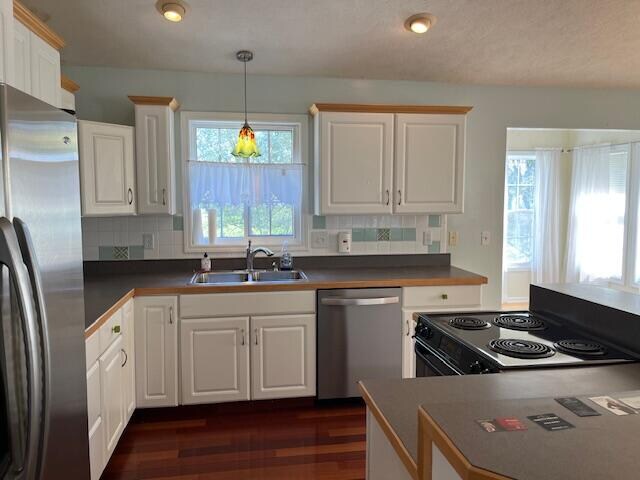 kitchen featuring dark wood-type flooring, white cabinets, appliances with stainless steel finishes, and a sink