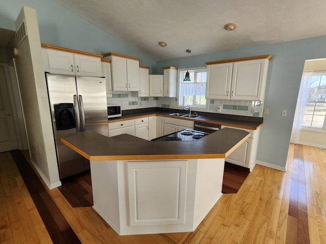 kitchen with a wealth of natural light, stainless steel refrigerator with ice dispenser, a sink, backsplash, and dark countertops