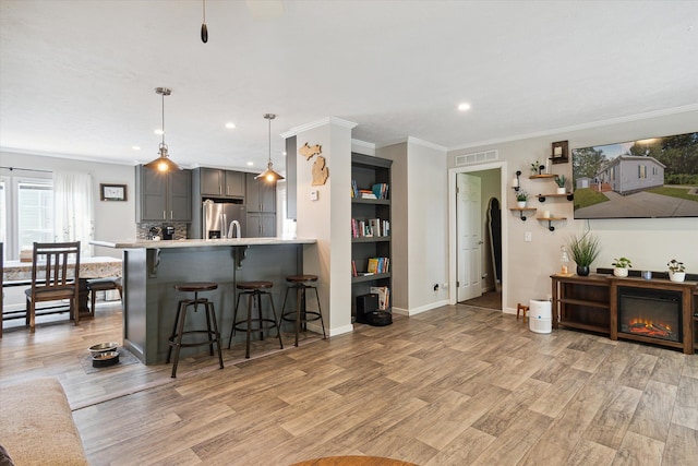 kitchen featuring pendant lighting, gray cabinets, light hardwood / wood-style floors, a kitchen bar, and stainless steel fridge with ice dispenser