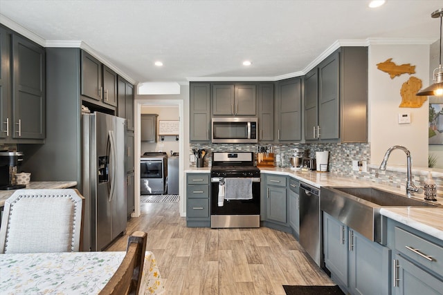 kitchen with gray cabinetry, decorative light fixtures, sink, and appliances with stainless steel finishes