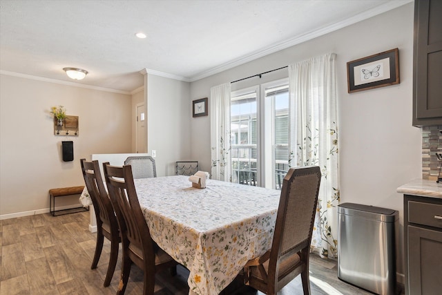 dining space with light hardwood / wood-style flooring and ornamental molding