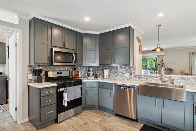 kitchen featuring pendant lighting, backsplash, crown molding, sink, and stainless steel appliances