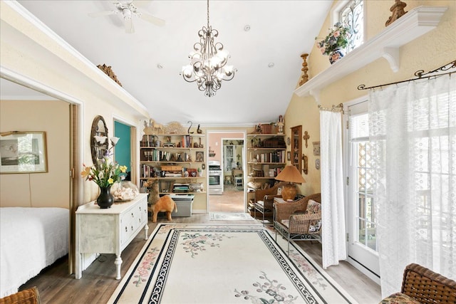 interior space featuring lofted ceiling, wood-type flooring, ornamental molding, and ceiling fan with notable chandelier