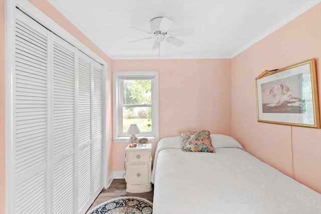 bedroom with hardwood / wood-style flooring, ceiling fan, crown molding, and a closet