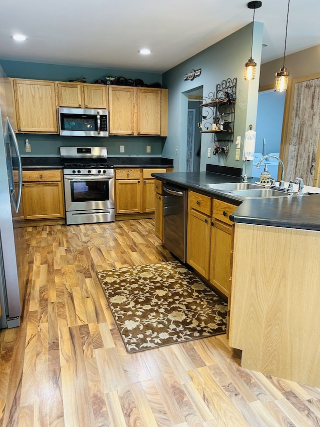 kitchen featuring sink, hanging light fixtures, light hardwood / wood-style floors, and appliances with stainless steel finishes