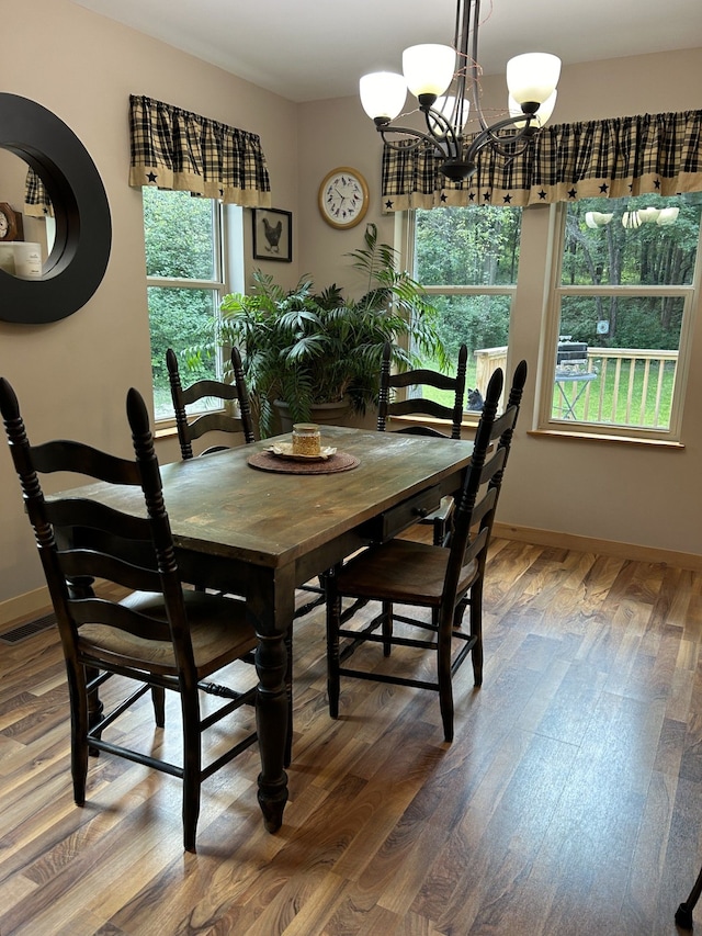 dining room with hardwood / wood-style floors, a wealth of natural light, and an inviting chandelier