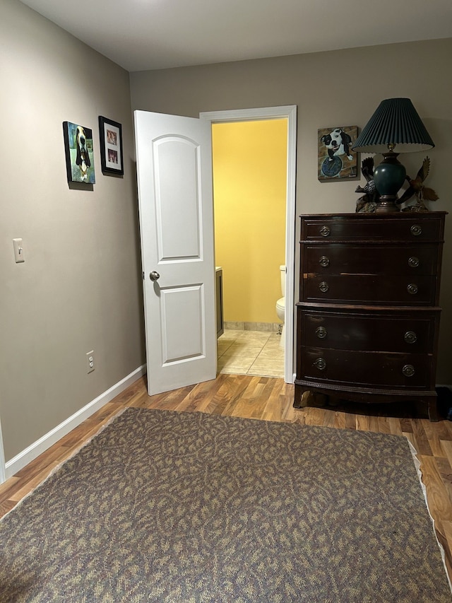 bedroom featuring ensuite bath and hardwood / wood-style flooring