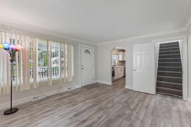 foyer entrance with light wood-type flooring and ornamental molding