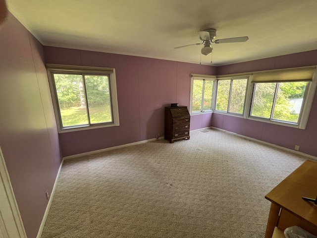 carpeted empty room featuring ceiling fan and a wealth of natural light