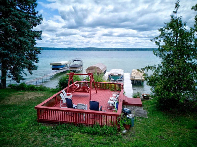 deck featuring a lawn, a boat dock, and a water view