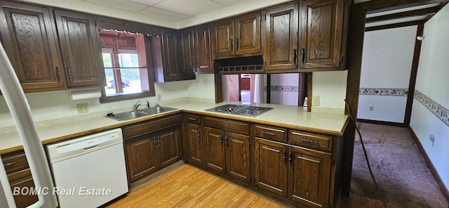 kitchen with light wood-type flooring, a drop ceiling, white dishwasher, stainless steel gas cooktop, and sink